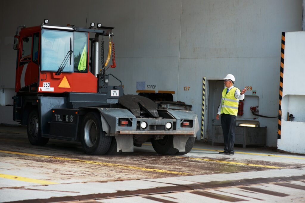 A manager standing at a loading dock signaling a truck to reverse