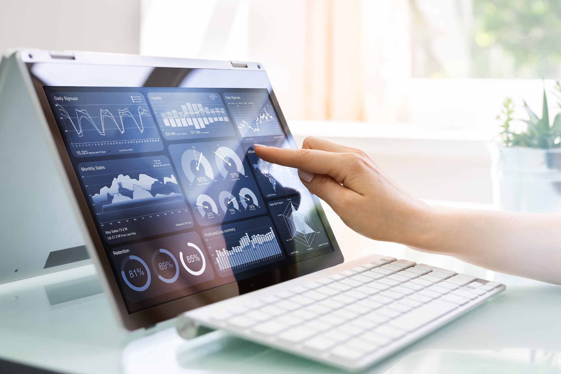 A person uses a touchscreen tablet displaying multiple data analytics graphs and charts focused on IT cost optimization, with a wireless keyboard in front.